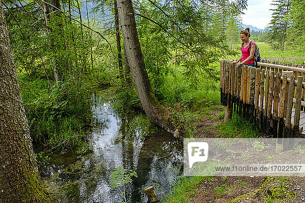 Wanderin bewundert die durch das Naturschutzgebiet Ettaler Weidmoos fließende Ammer im Frühling