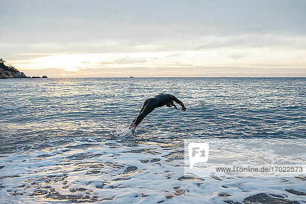Male swimmer jumping into sea water