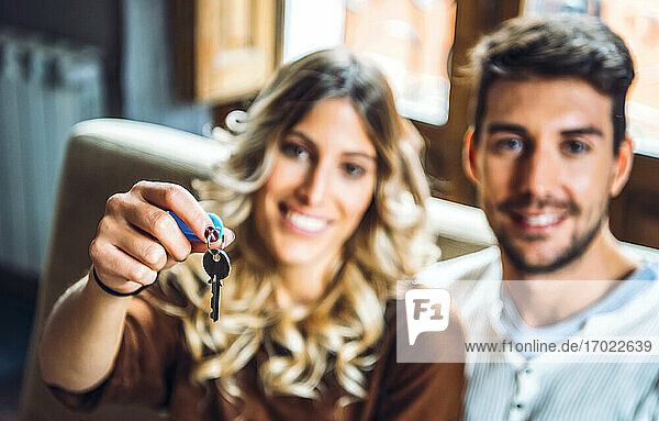 Portrait of happy young couple holding keys of new home