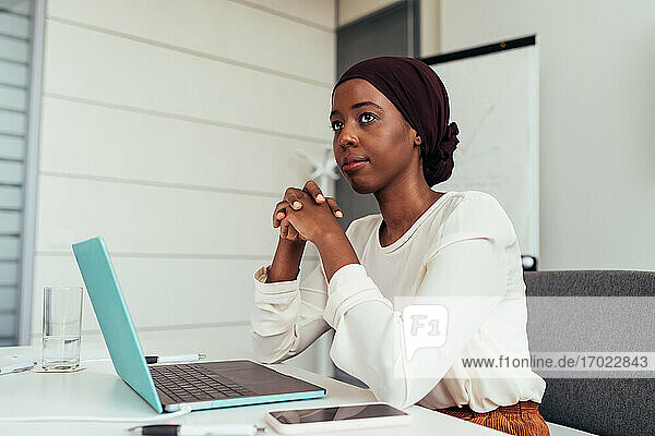 Geschäftsfrau im Büro mit Laptop  nachdenklich