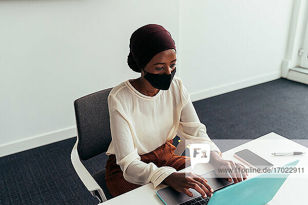 Frau arbeitet am Laptop  trägt Gesichtsmaske