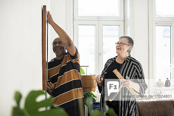 Lächelnde Senior Paar hängen Malerei an der Wand zu Hause