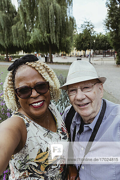Lächelndes älteres Paar nimmt Selfie im Park während des Urlaubs