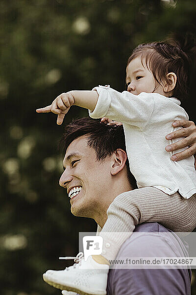 Männliches Kleinkind  das auf die Schulter des Vaters auf dem Spielplatz zeigt