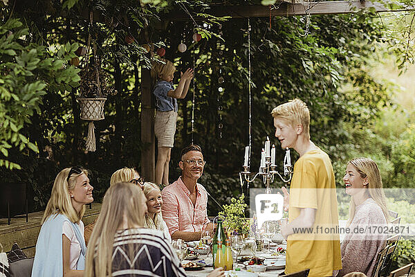 Boy talking with family during social event in back yard