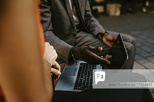 Ausgeschnittenes Bild eines männlichen Unternehmers  der mit einer weiblichen Kollegin über einem Laptop diskutiert