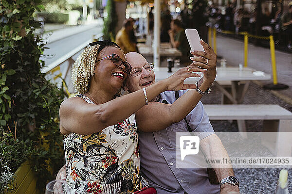 Fröhliches heterosexuelles Paar nimmt Selfie auf Smartphone im Café