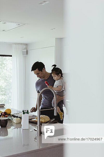 Vater trägt männliches Kleinkind bei der Zubereitung von Essen in der Küche