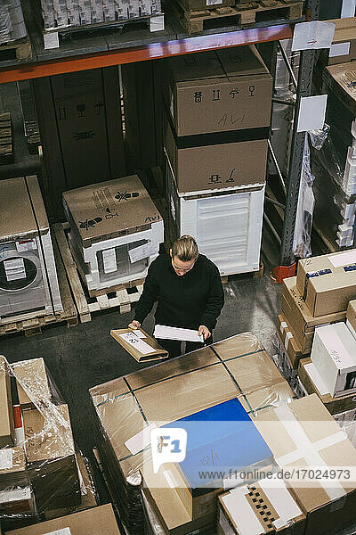 High angle view of businesswoman examining packages at distribution warehouse
