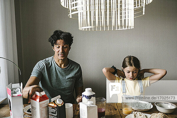 Vater sitzt mit Tochter beim Frühstück zu Hause