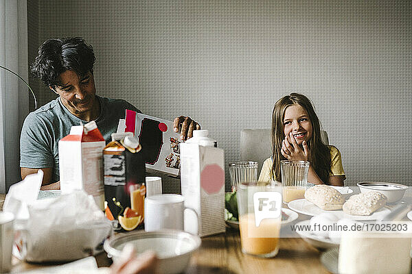 Smiling father and daughter having breakfast together at dining table