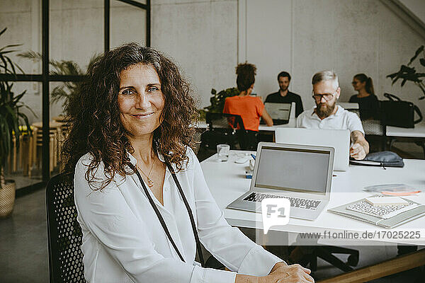 Porträt von lächelnden Geschäftsfrau sitzt von Laptop in Coworking Büro