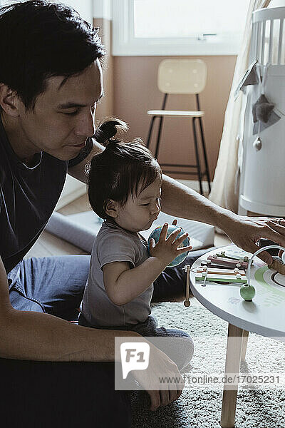 Father and baby son playing with toy in living room