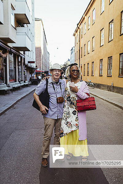 Aktive ältere Paare mit Armen um stehend auf der Straße in der Stadt