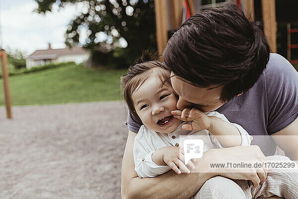 Vater küsst lächelnd Baby Sohn im Park