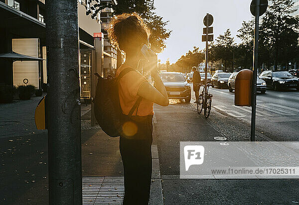 Geschäftsfrau im Gespräch über Smartphone beim Stehen auf dem Fußweg in der Stadt