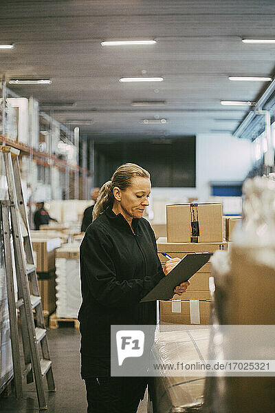 Reife weibliche Arbeitskraft  die Pakete im Logistiklager analysiert
