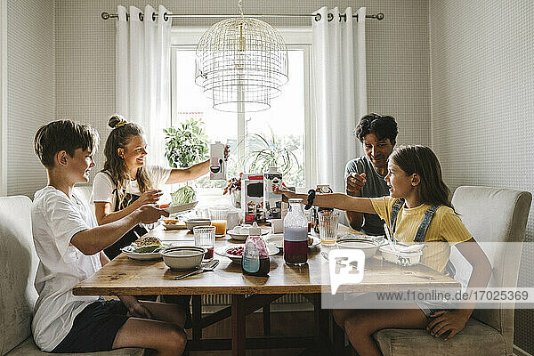 Eltern frühstücken mit Kindern am Tisch zu Hause