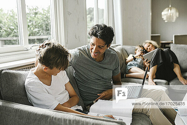 Happy father with son doing his homework at home