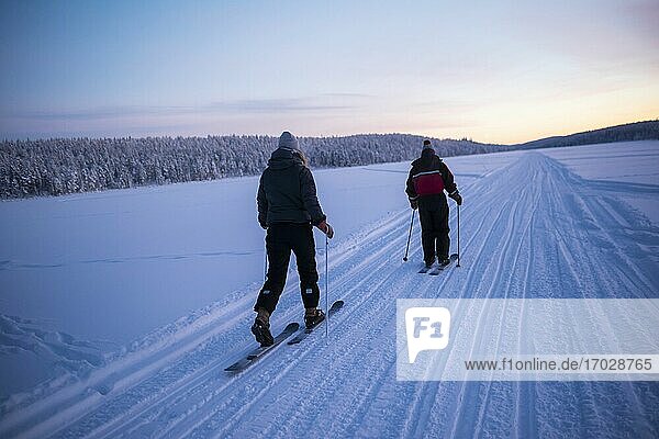 Skifahren auf dem zugefrorenen See von Torassieppi bei Sonnenuntergang  Lappland  Finnland