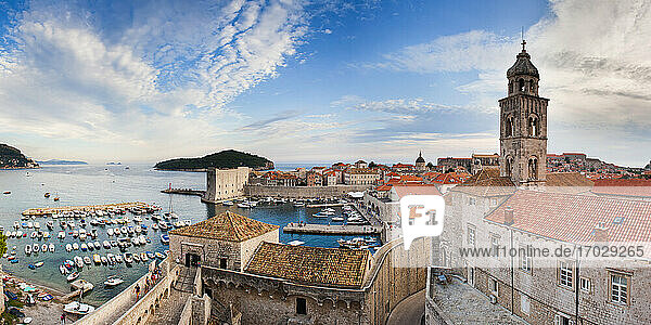 Panoramic photo of Dubrovnik Old Town Harbor and the Dominican Monastery from Dubrovnik city walls  Dalmatia  Croatia. This panoramic photo  taken from the City Walls shows Dubrovnik City Harbor and the Dominican Monastery in UNESCO World Heritage listed Dubrovnik Old Town  with Lokrum Island in the background. Dubrovnik City Walls are without a doubt the highlight of visiting this beautiful  historic old town on the Dalmatian Coast of Croatia. Dubrovnik City Walls offer unrivalled panoramic views over the old town harbor  Lokrum Island  Dominican Monastery  Adriatic Sea and Lokrum Island.