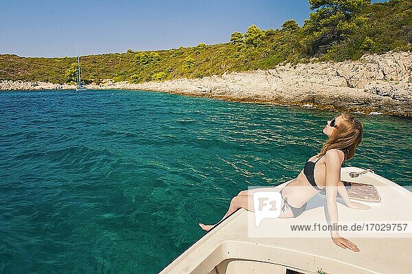 Foto einer Touristin in einem Luxusurlaub auf den Pakleni-Inseln  Insel Hvar  Dalmacija  Dalmatien  Kroatien. Dies ist ein Foto einer weiblichen Touristin im Luxusurlaub  die auf einem Boot auf den Pakleni-Inseln in der Nähe der Insel Hvar in Dalmacija  Dalmatien  Kroatien  ein Sonnenbad nimmt.