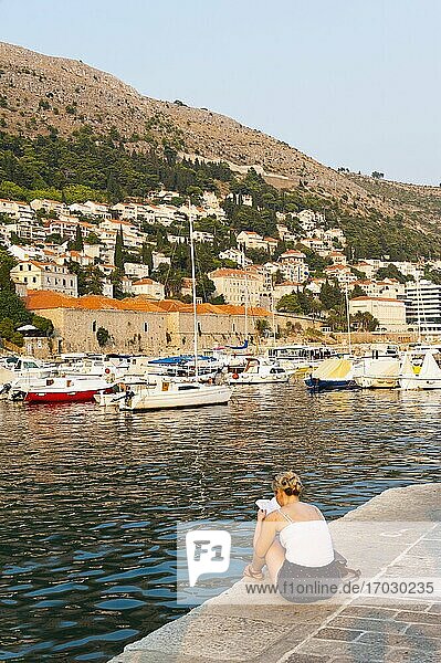 Foto eines lesenden Touristen im Hafen der Altstadt von Dubrovnik  dalmatinische Küste  Kroatien. Dies ist ein Foto von einem Touristen  der im Hafen der Altstadt von Dubrovnik  Dalmatinische Küste  Kroatien  liest.