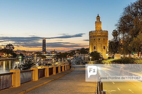 Boardwalk at the river Rio Guadalquivir with illuminated Torre del Oro  in the back Torre Sevilla  sunset  blue hour  Sevilla  Andalusia  Spain  Europe