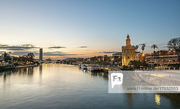 View over the river Rio Guadalquivir with Torre del Oro  promenade and Puente de Triana  in the back Torre Sevilla  sunset  blue hour  Sevilla  Andalusia  Spain  Europe