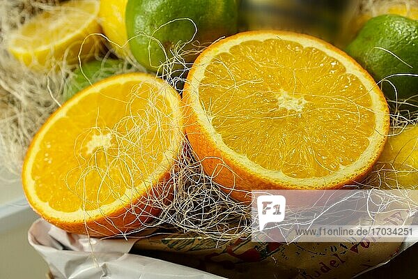 Komposition aus zwei Orangenhälften  zwei grünen Limetten und gelben Zitronen im Hintergrund. Nahaufnahme Fotografie.