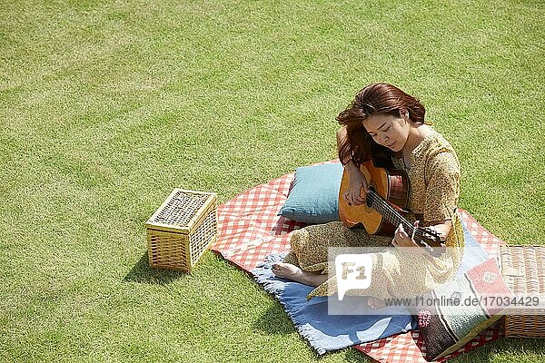 Japanese woman playing guitar in the garden