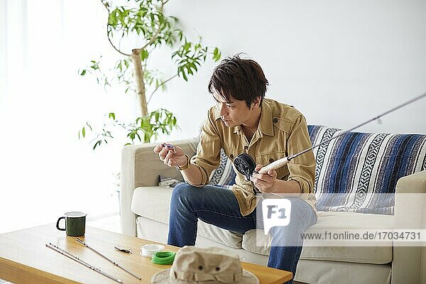 Japanischer Mann reinigt Angelrute zu Hause
