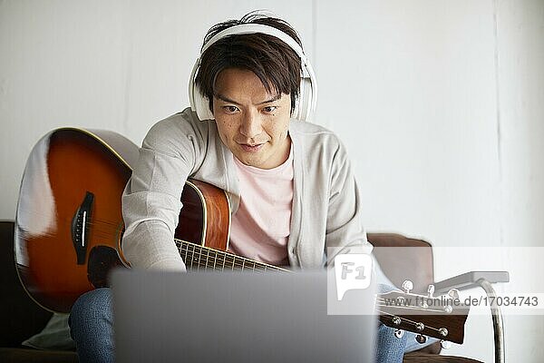Japanischer Mann spielt Gitarre zu Hause