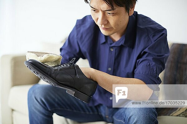 Japanischer Mann putzt Schuhe zu Hause