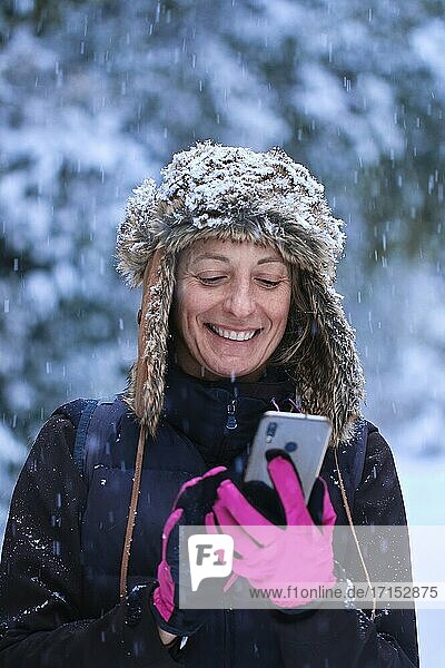 Caucasian young woman enjoying with a mobile phone in snow outdoor in winter time. Navarre  Spain  Europe.