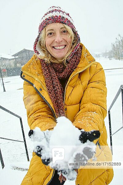 Kaukasische junge Frau macht einen Schneeball im Freien im Winter. Navarra  Spanien  Europa.