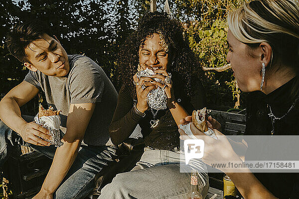 Junge Frau isst Essen mit Freunden im Park