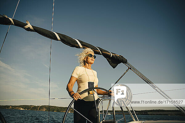Aktive ältere Frau Segelboot gegen den Himmel im Meer an einem sonnigen Tag