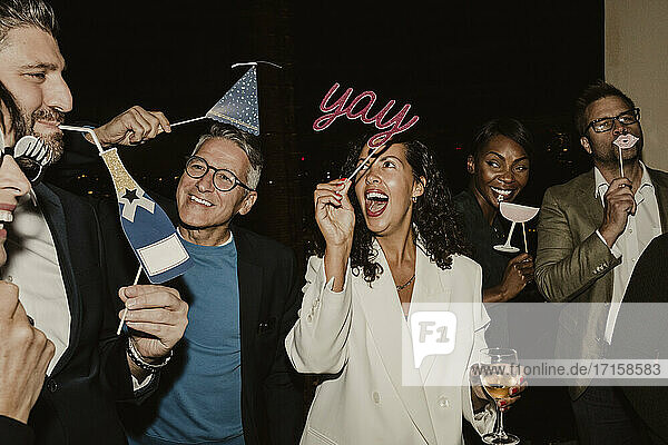 Cheerful business people enjoying with props during company party at night