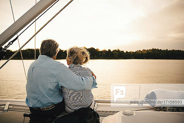 Rückansicht eines älteren Paares  das das Meer bei Sonnenuntergang bewundert