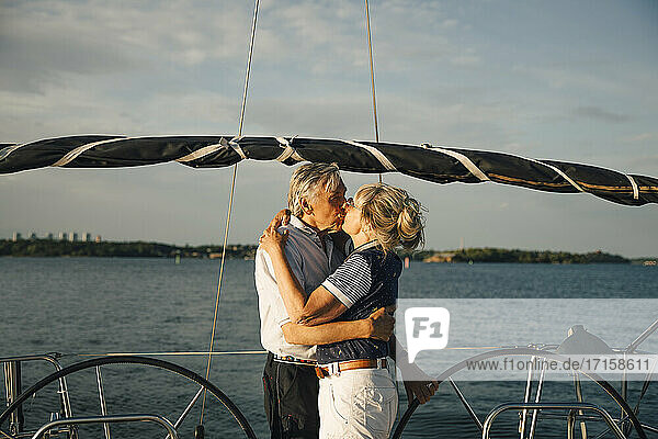Senior Paar Lippe küssen in Boot gegen Meer und Himmel am sonnigen Tag
