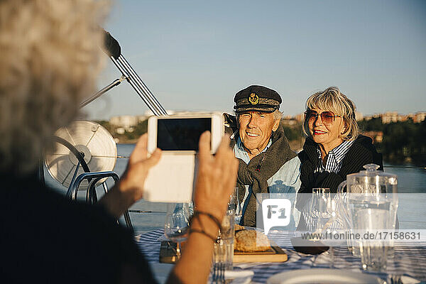 Ausgeschnittenes Bild von Frau fotografieren ältere Paar sitzt in Boot auf sonnigen Tag