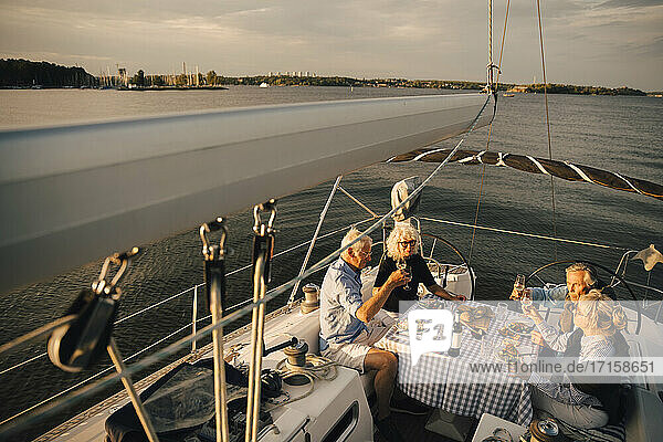 Ältere Paare stoßen mit Weingläsern an  während sie ihre Freizeit im Boot verbringen