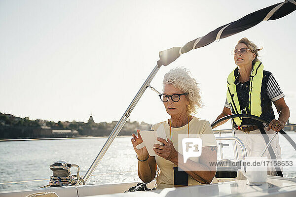 Senior Frau navigieren auf Smartphone  während weibliche Segelboot gegen den Himmel