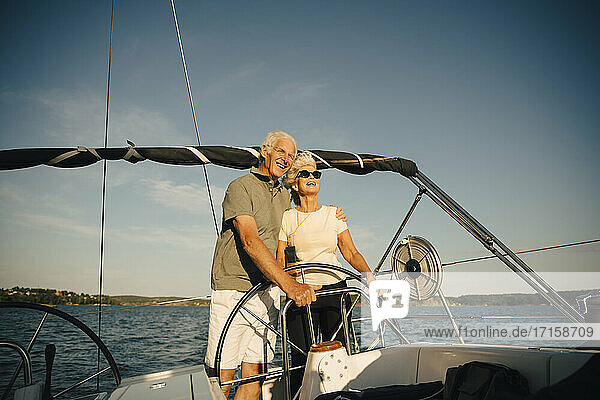 Lächelnde Senior Paar mit Arm um in Segelboot gegen Himmel im Meer