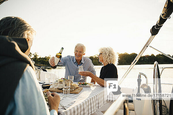 Fröhliche ältere Freunde  die Wein trinken  während sie ihre Freizeit auf einem Segelboot verbringen