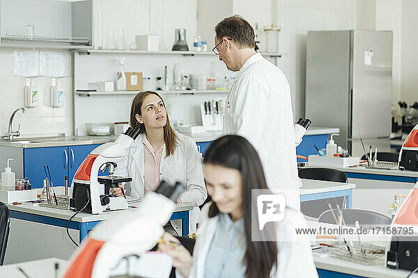 Schüler und Lehrer mit Mikroskop im naturwissenschaftlichen Unterricht