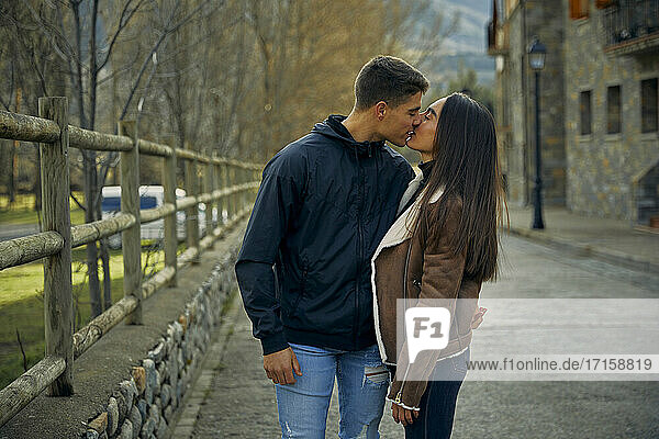 Girlfriend and boyfriend kissing passionately with eyes closed in town