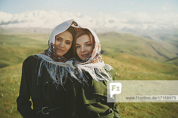 Smiling lesbian couple with headscarf at meadow