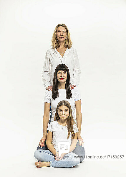 Caucasian girl sitting while women behind her against white background